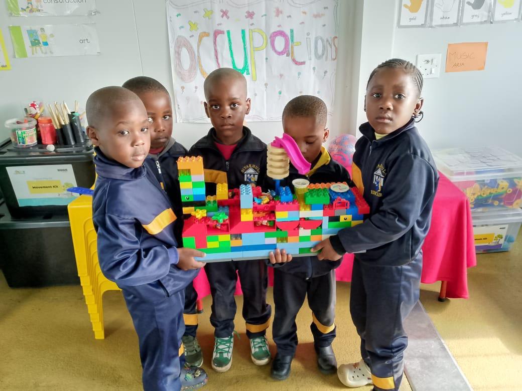 Learners proudly holding a large block construction