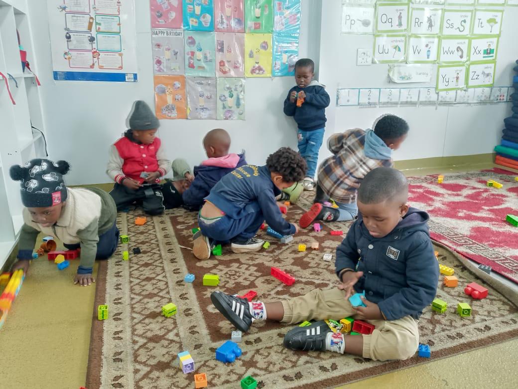 Toddlers playing with building blocks on the classroom carpet