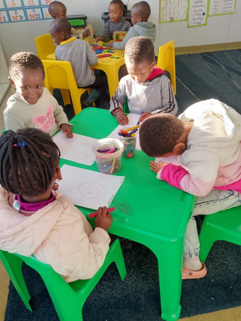 Children drawing and colouring at classroom tables